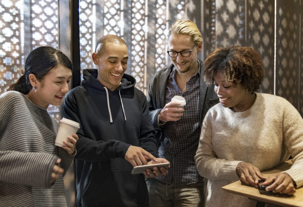 smiling group of friends watching viral video on smartphone