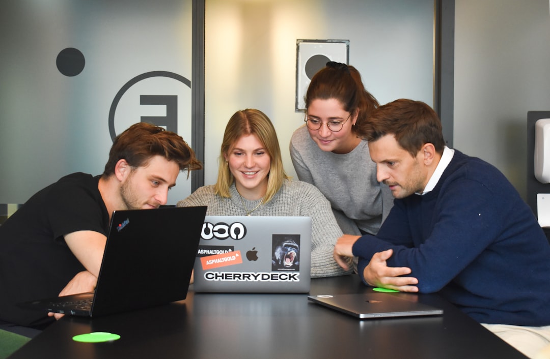 Growth Rocket Four people collaborating around a laptop on a table in a modern office