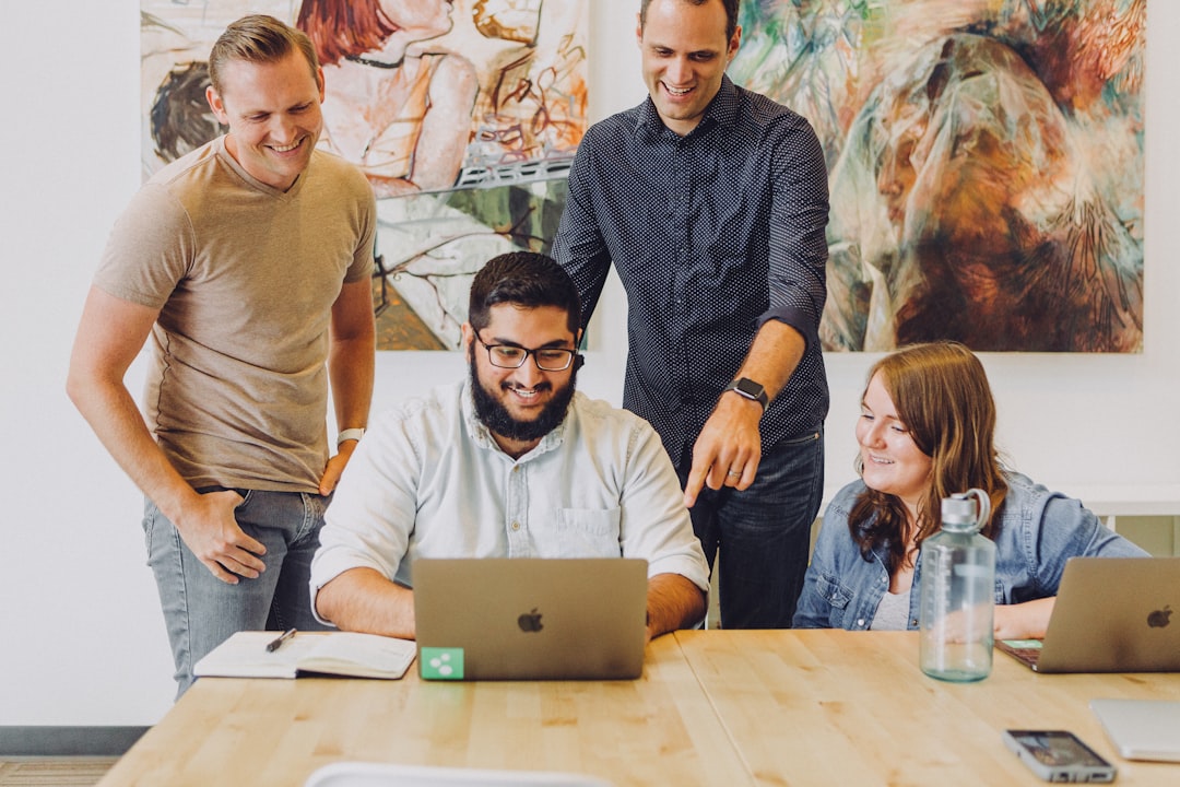 Growth Rocket four coworkers smiling around laptop at table